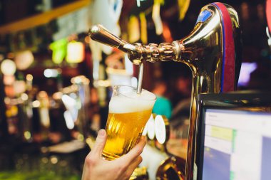 Barmen elleri bardağa bira dolduruyor..