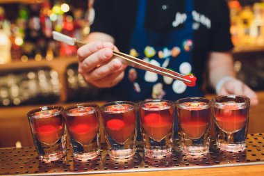 Barmen adam profesyonel bir yazıcı ile pub bar sıcak alkol çekim yapma. Barmen, bir bardak daha hafif ışıklar. Gece kulübünde rahatlayın. Sıcak ateş içer. Parti sağlar.