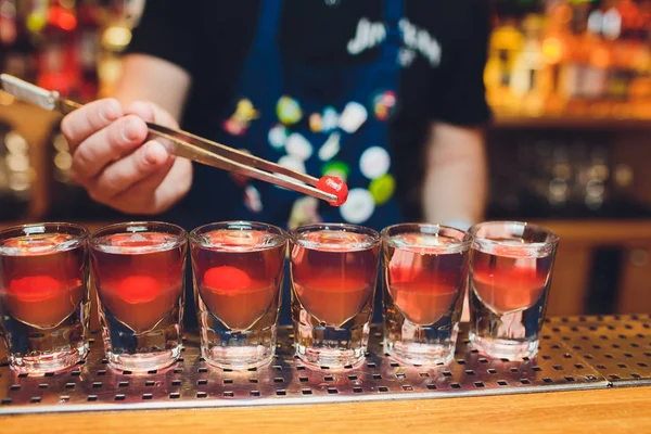 Barkeeper Mann macht heiße Alkohol-Aufnahmen an der Bar in der Kneipe mit einem professionellen Brenner. der Barkeeper zündet ein Feuerzeug über einem Glas an. Entspannen Sie im Nachtclub. Heißgetränke. lässt die Partei. — Stockfoto