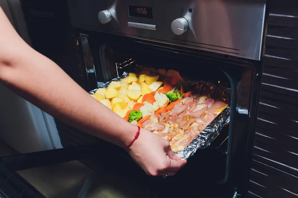 Повар берет готовую жареную курицу с овощами из духовки. Концепция приготовления пищи . — стоковое фото