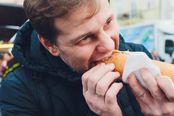 Крупный план портрета голодного человека в очках, поедающего хот-дог на открытом воздухе . — стоковое фото