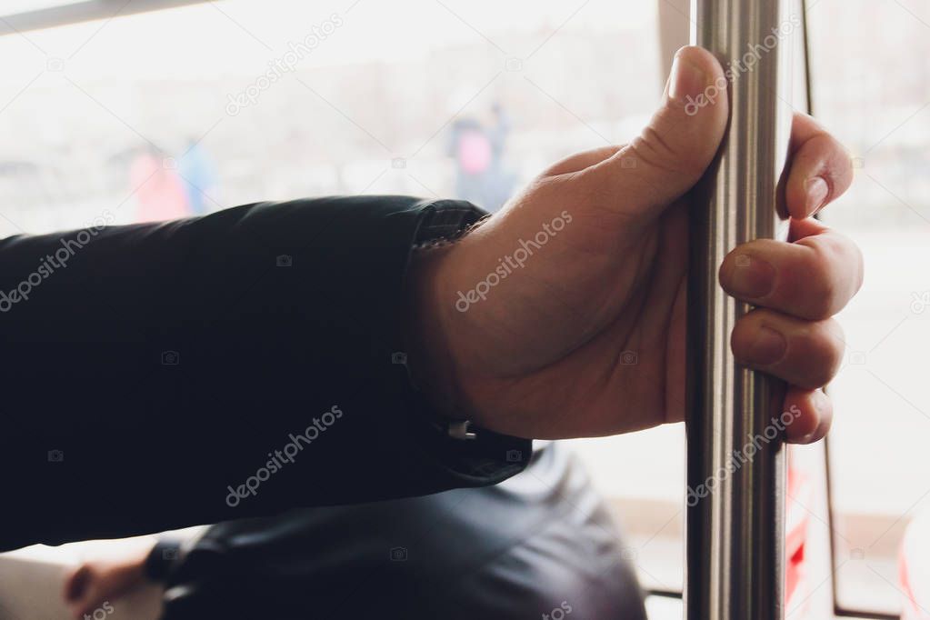 closeup man hand holding handrail inside the train.