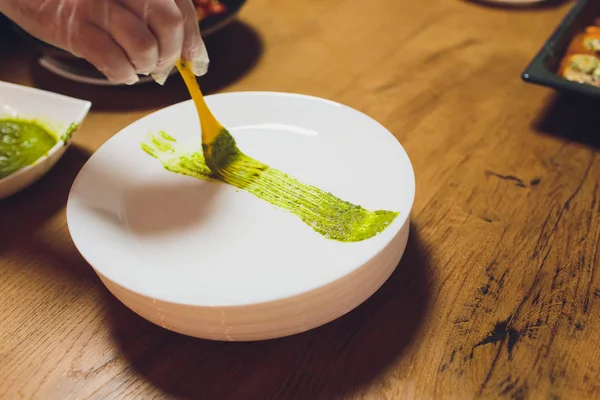 Bir erkek şef siyah önlük bir restoran mutfakta bir salata tabağı süsler. maşa ile bir elin yakın çekim. — Stok fotoğraf