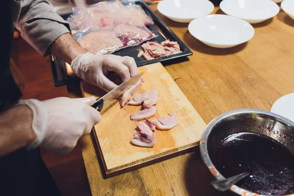 Chef cortando la carne en una tabla de madera. — Foto de Stock