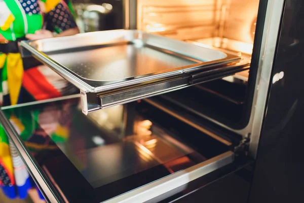 Empty open electric oven with hot air ventilation. New oven. Door is open and light is on.