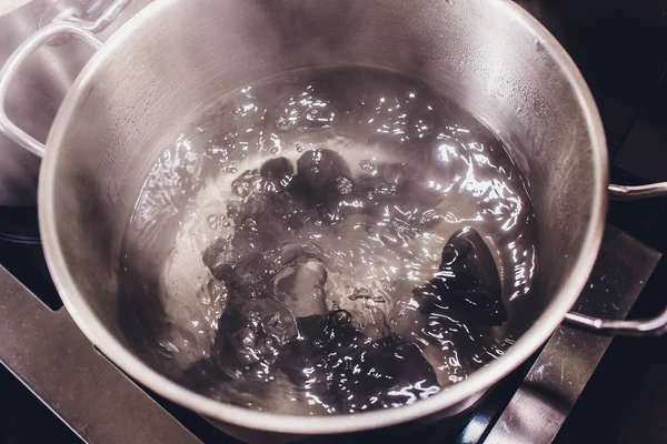 Khinkali of dumplings worden gekookt in gekookt water op de kachel in een steelpan door middel van stoom. Koken. zwarte kleur. — Stockfoto