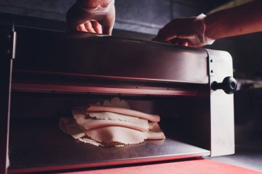 Şef hamur pasta sac fırın Baker şekillendirme hamur haddelenmiş pasta metal çalışma masası closeup el işlemleri ekmek khinkali hamur rulo makinesi ince makarna levha Üst görünüm hazırlama.