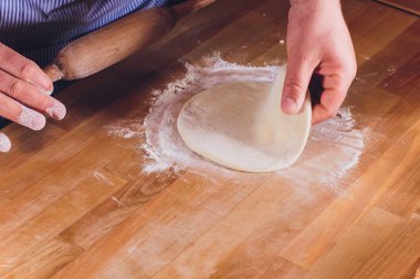 Hamur Baker yoğurun tabakası nın elleri, siyah arka plan üzerinde izole.