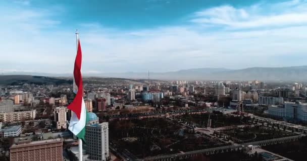 Flaga Tadżykistanu na masztem przeciwko błękitnym niebie nowoczesnych tonowanie — Wideo stockowe