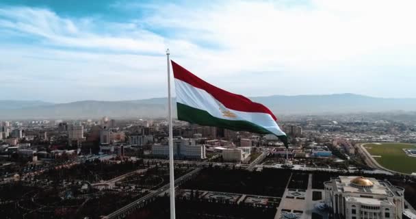 Flaga Tadżykistanu na masztem przeciwko błękitnym niebie nowoczesnych tonowanie — Wideo stockowe