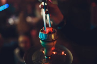 adam nargile atmosferik içinde nargile üzerinde kömürleri değiştirerek.