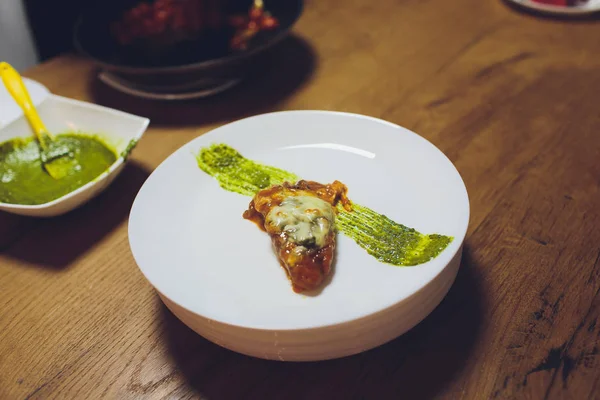 Un chef masculino decora un plato de ensalada en una cocina de restaurante en un delantal negro. primer plano de una mano con pinzas . —  Fotos de Stock