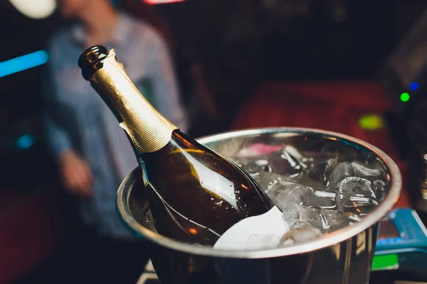 Пляшка шампанського в льодовому відрі на фоні ресторану . — стокове фото