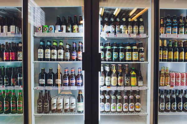 UFA, RUSIA 5, 2018: Varias botellas de cerveza artesanal, microcervecera, IPA, nacional e importada de todo el mundo en la exhibición de estantes en el refrigerador del supermercado. Alcohol bebida de fondo. Estilo panorámico . — Foto de Stock