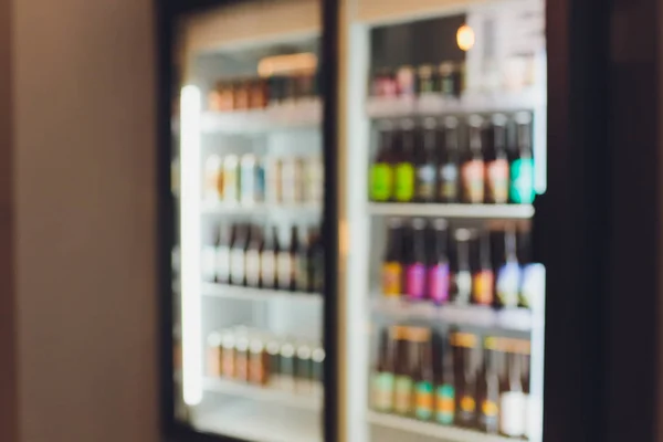 На задньому плані розмиті розфокусовані пива охолоджуються в холодильнику, морозильнику або шельфі холодильника. Розфокусоване розмите нічне життя, нічний клуб, бар, паб, магазин або продуктовий фон концепція зображення . — стокове фото