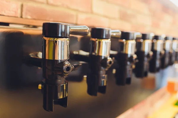 Een rij vernikkelde biertap kranen in de bottelen Store. — Stockfoto