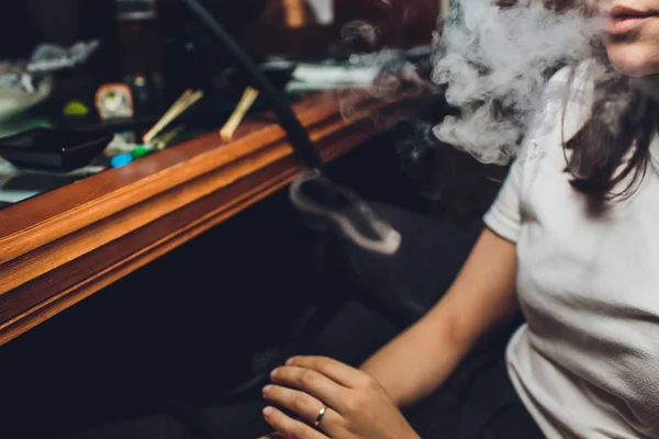 Bella ragazza in una camicetta bianca fuma un narghilè all'interno del bar . — Foto Stock