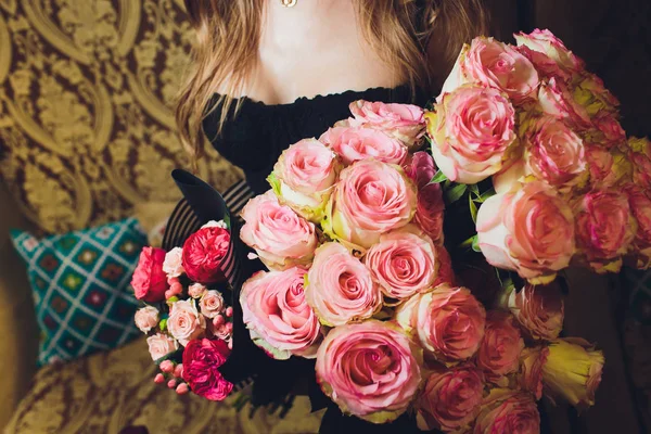 Рука красивої молодої жінки в чорній сукні тримає великий букет з рожевих троянд . — стокове фото