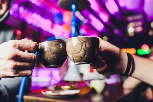 Profiel van de handen van een paar houden koffie kopjes over een tafel in de winter in een appartement. — Stockfoto