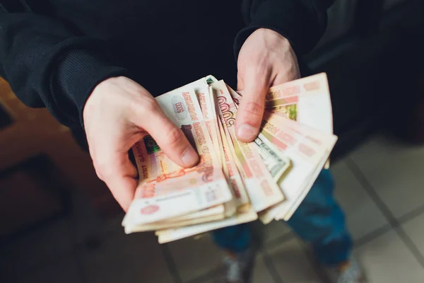 Un hombre tiene rublos y dólares en su mano, un hombre de negocios tiene dinero en su mano . — Foto de Stock