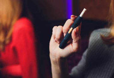 Isı yakmayan tütün ürünü teknolojisi. Sigara içmeden önce elinde e-sigara tutan kadın..