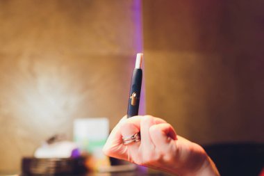 Isı yakmayan tütün ürünü teknolojisi. Sigara içmeden önce elinde e-sigara tutan kadın..