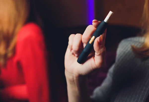 Technologie für hitzebeständige Tabakerzeugnisse. Frau hält vor dem Rauchen E-Zigarette in der Hand. — Stockfoto