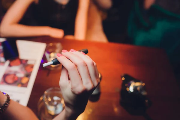 Tecnología de productos de tabaco sin combustión por calor. Mujer sosteniendo el cigarrillo electrónico en su mano antes de fumar. — Foto de Stock