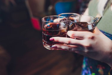 Erkek el atış ya da likör bardak ile tezahürat. Arkadaşlar atış veya likör ve şerefe içmek. Erkek el ile alkol bulanık bar arka plan üzerinde tezahürat. Parti ve tost kavramı.