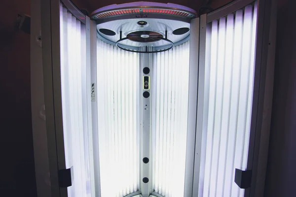 Vertikal gebräunte Turbo-Solarium-Lichtmaschine mit leuchtend blauem Licht UV-Lampen zur Bräunung und Hautpflege. leere Bräune modernes Solarium, innen. offene Solarium-Tür. Bedienfeld auf der Seite. — Stockfoto