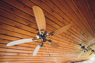 modern bir evin oturma odasında, üst ve sağ tarafta metin alanı ile, bir tonozlu ahşap tavan ile, maruz kalan bir destek kiriş üzerinde tavan fan.