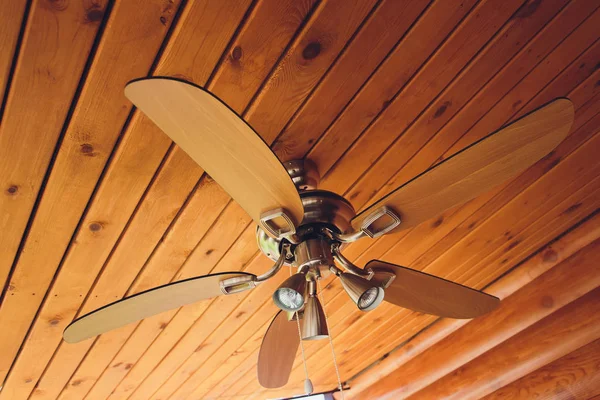 Ventilador de teto em um feixe de suporte exposto, com um teto de madeira abobadada, na sala de estar de uma casa moderna, com espaço para texto no lado superior e direito . — Fotografia de Stock