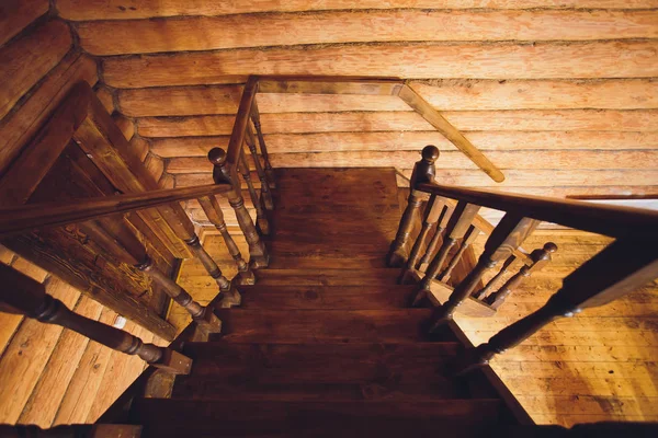 Oude vierkante spiraal trap met donker bruine houten leuningen, deels verlicht door Windows. Uitzicht vanaf de top. — Stockfoto