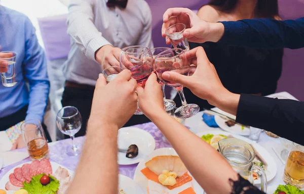 Menselijke handen met glazen rode wijn rammelende ze boven tafel geserveerd. — Stockfoto