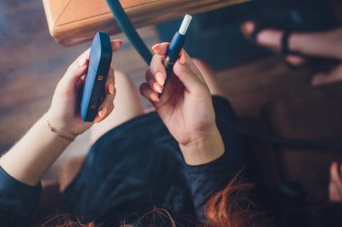 Isı yakmayan tütün ürünü teknolojisi. Sigara içmeden önce elinde e-sigara tutan kadın..