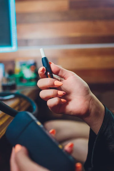 Technologie tabákových výrobků bez spalování tepla. Žena drží e-cigaretu v ruce před kouřením. — Stock fotografie