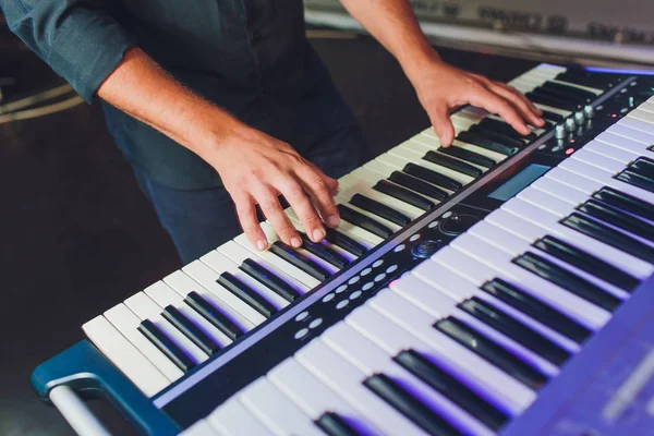 Homem tocando sintetizador de teclado musical eletrônico por mãos em teclas brancas e pretas em estúdio de gravação . — Fotografia de Stock