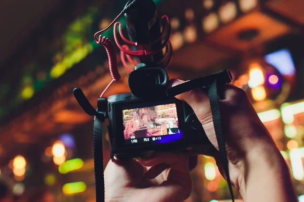 Hombre sosteniendo la cámara de fotos en la mano al aire libre, fotógrafo concepto de cámara sin espejo . — Foto de Stock