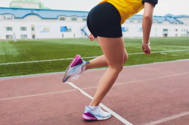 Genç kadın atlet bir yarışta start çizgisinde kapalı başlatılması kırpılmış bir kadeh. Parlak güneş ışığı ile başlangıç satırından sprint kadın runner başladı.