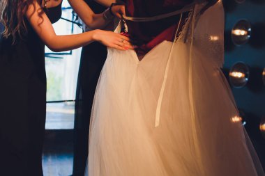 Muhteşem, beyaz lüks elbiseli gelin düğün için hazırlanıyor. Sabah hazırlıkları. Elbise giydiren kadın.