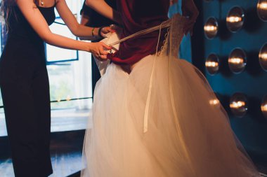 Muhteşem, beyaz lüks elbiseli gelin düğün için hazırlanıyor. Sabah hazırlıkları. Elbise giydiren kadın.