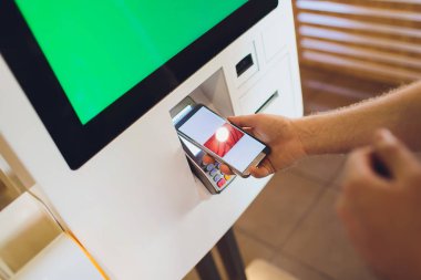 Bir adam fast-food restoranda elektronik menü ile dokunmatik ekran terminalinde yiyecek sipariş.
