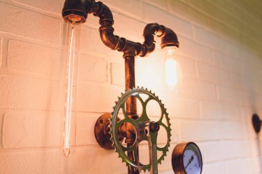 İç mimari tarzı tasarım unsuru Steampunk. Lamba ampul aydınlatmalı ekipman kapalı asılı aydınlatma demir sanayi dişli cogwheels Zincir Dişli üzerinde sabit.