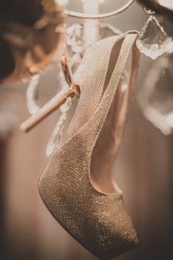 Avize üzerinde asılı beyaz düğün ayakkabıları.