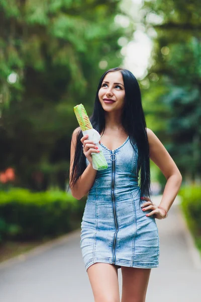 Ragazza piuttosto soleggiata che tiene succosa shawarma pollo sulla natura. Primo piano del fast food all'aperto . — Foto Stock