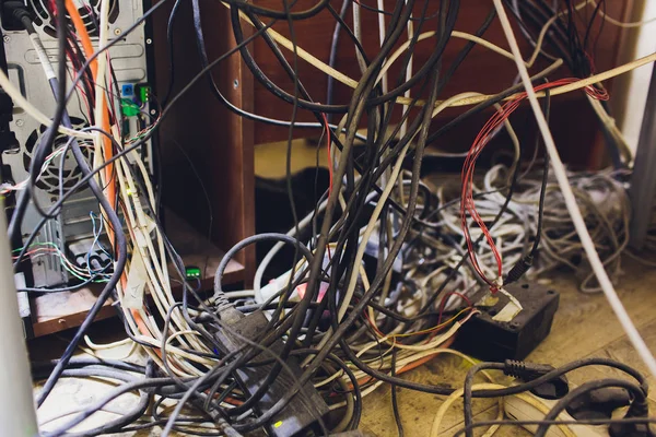 Conceito de desordem no cargo. Fios eléctricos desenrolados e emaranhados debaixo da mesa . — Fotografia de Stock