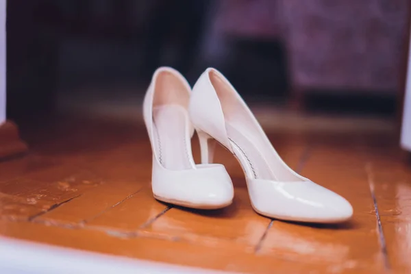 Close Up Still Life of Pair of Plain White sapatos de noiva com salto alto descansando no chão de madeira rústica ou mesa com espaço de cópia em foco seletivo . — Fotografia de Stock