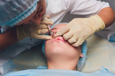 Dudak Büyütme. Güzel Genç Kadınlar Ağız Hyaluronik Asit Enjeksiyon alma. Seksi Kadın Dudakları için Güzellik Prosedürü Yapıyor Beautician Eller Closeup. Kozmetoloji Tedavisi. Yüksek Çözünürlük.