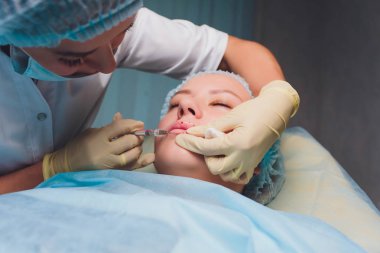 Dudak Büyütme. Güzel Genç Kadınlar Ağız Hyaluronik Asit Enjeksiyon alma. Seksi Kadın Dudakları için Güzellik Prosedürü Yapıyor Beautician Eller Closeup. Kozmetoloji Tedavisi. Yüksek Çözünürlük.