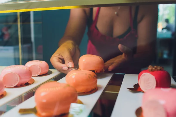 Primer plano de los vendedores manos sacando pastel de escaparate en panadería . — Foto de Stock